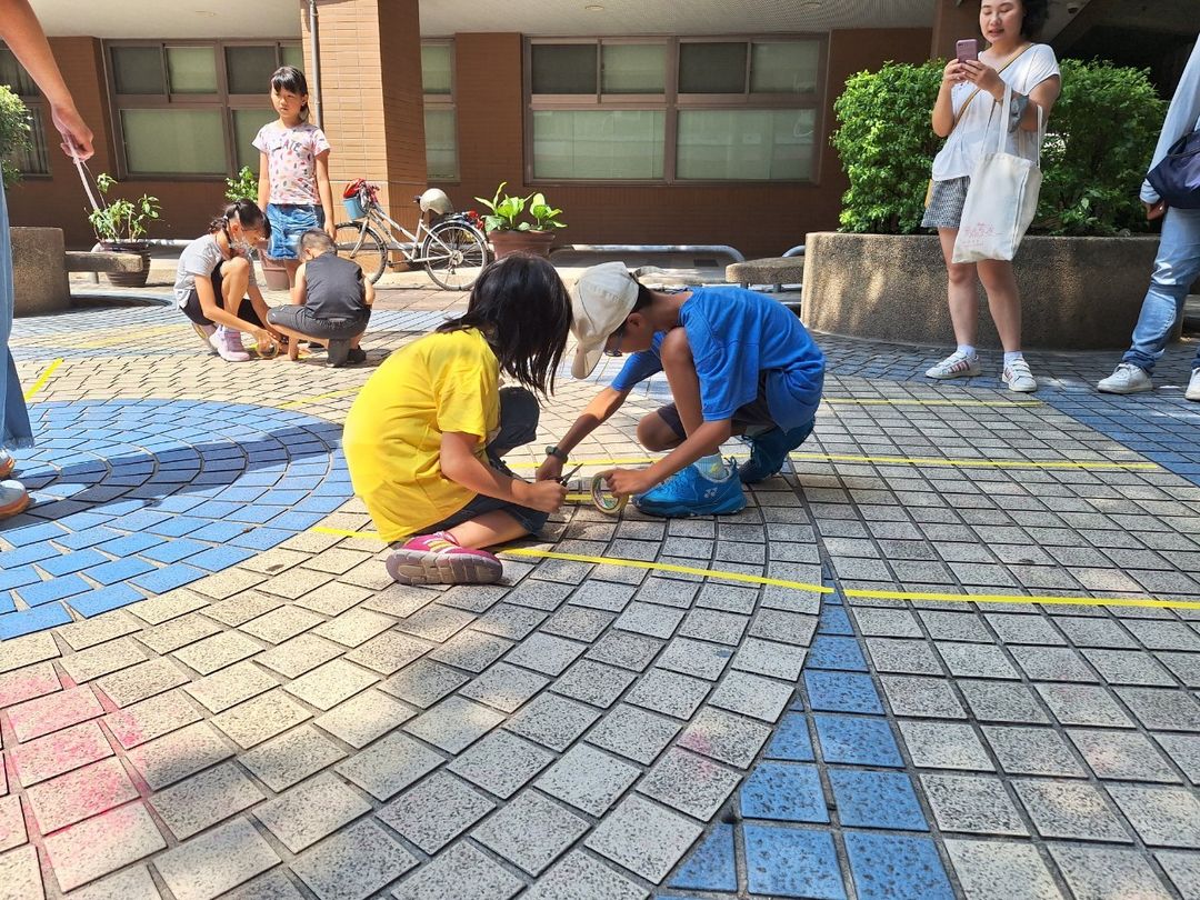 <p>「真人版跳棋」由小朋友們分工合作利用地磚的花色，以貼地膠帶貼出棋盤格子。</p>