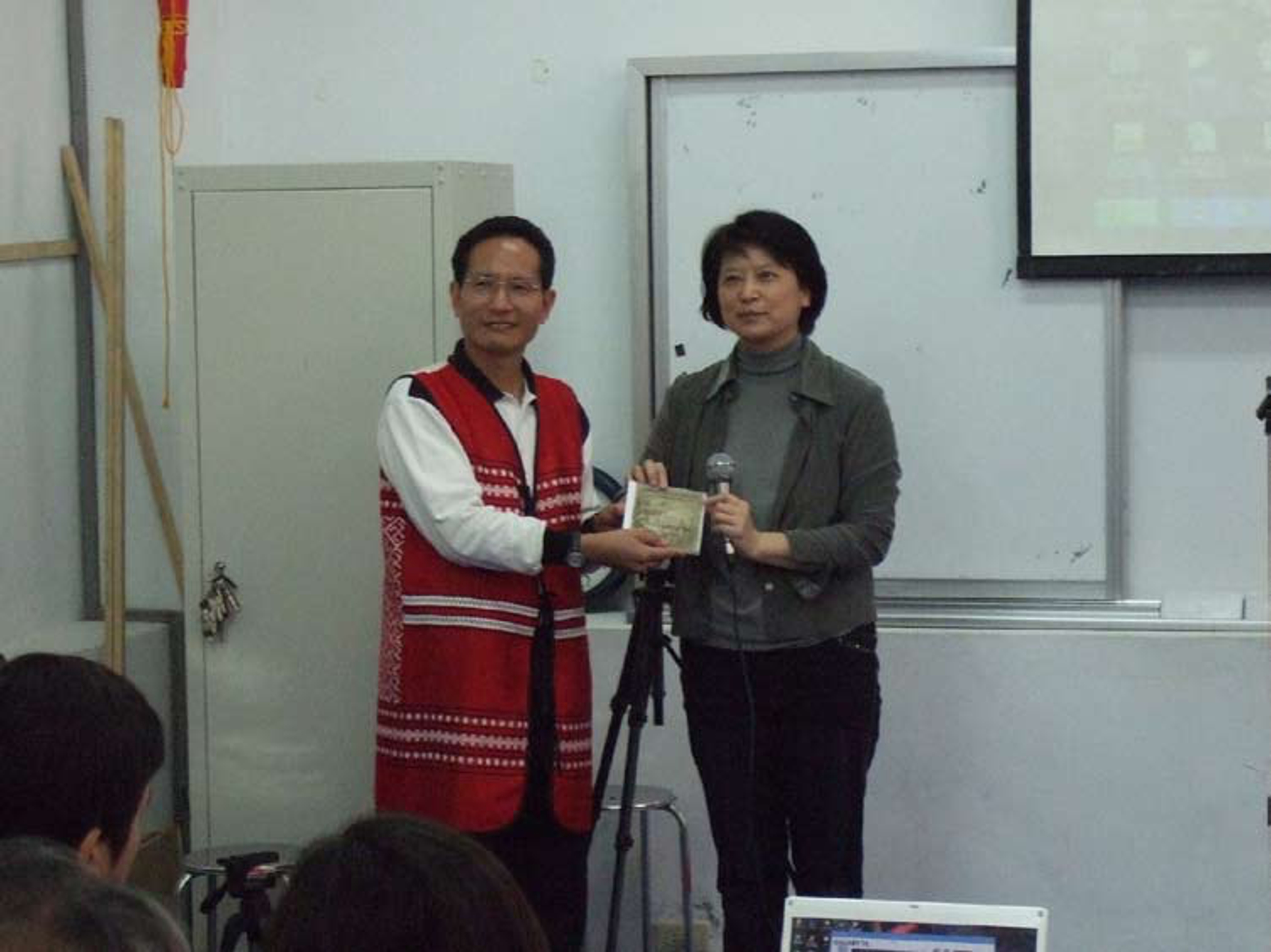 <p class="ql-align-center">放映會後將影片光碟交送新竹縣五峰鄉賽夏族文化藝術協會理事長趙金山。胡家瑜提供,2007年12月8日攝於大隘部落賽夏族矮靈祭場文物館視聽室。</p>