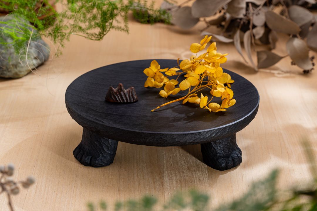 <p>盤面使用車床做出微凹的曲面，並以雕刻刀在側邊留下彷彿毛流的刻紋，讓盤面視覺延伸到雕塑概念製作的盤腳。底下三隻貓腳皆以手工一一刻製，每個三腳貓盤都是獨一無二。</p>